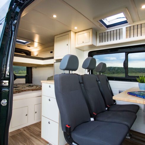 Der Innenraum eines MAN TGE Campervans von der Vanlifemanufaktur - mit exklusiv nachgerüsteten Schnierle Einbausitzbank für drei Personen. Im Hintergrund ein Doppelstockbett für bis zu vier Personen!